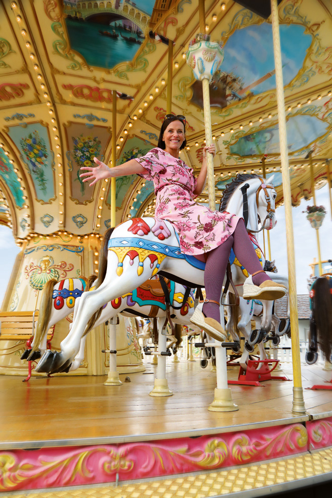 Dame sitz auf einem Karousell und trägt lila Kompressionsstrümpfe