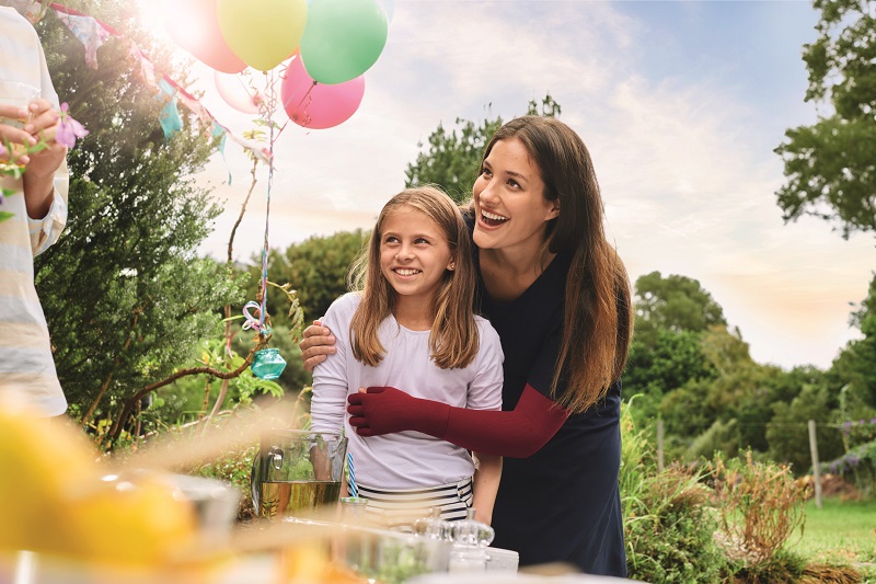 Geburtstagsfeier Mutter und Kind. Mutter trägt rote Armkompressionsstrümpfe